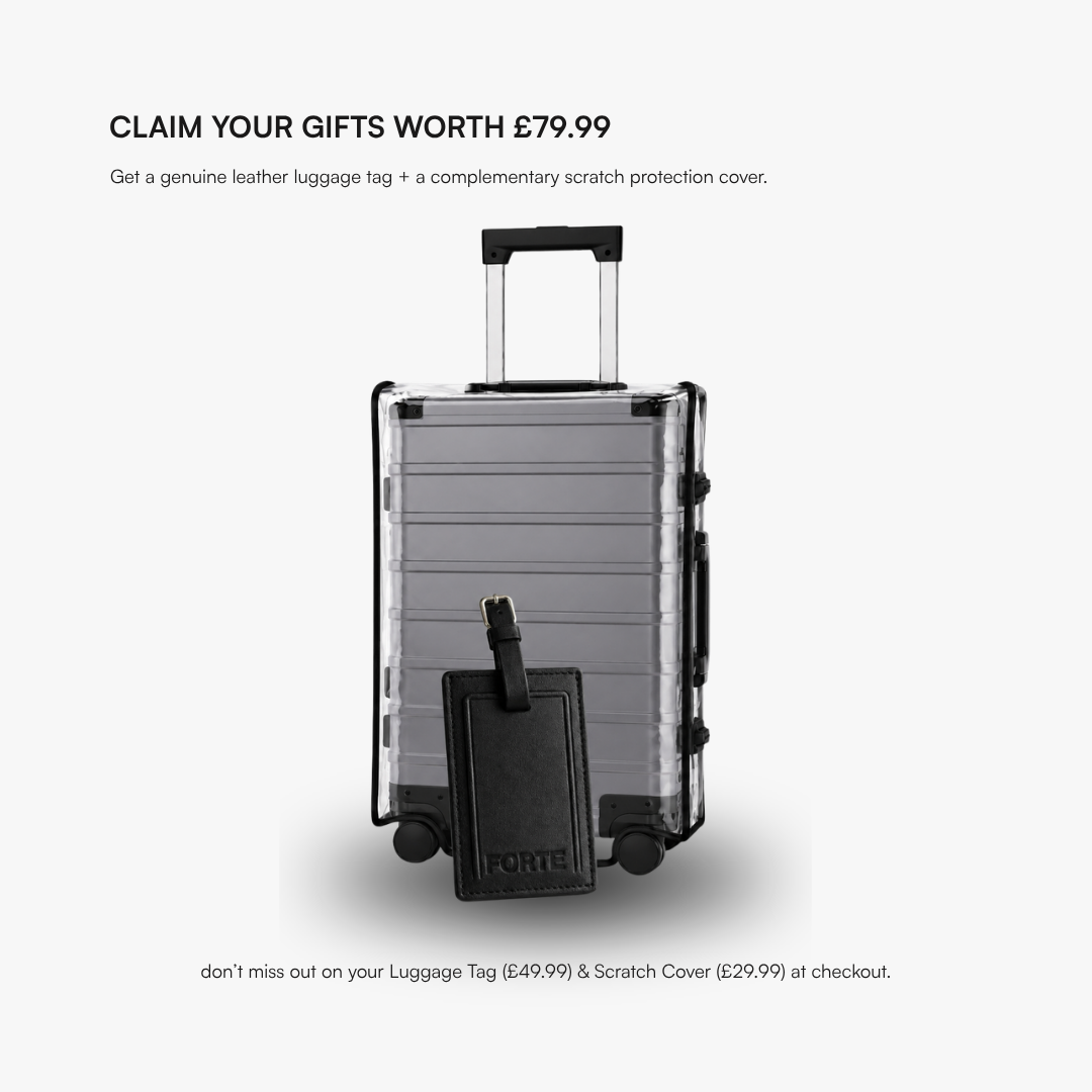 A Aluminium hard-shell suitcase with a black telescoping handle and four wheels, shown with a black luggage tag in front. Text above reads 'CLAIM YOUR GIFTS WORTH £79.