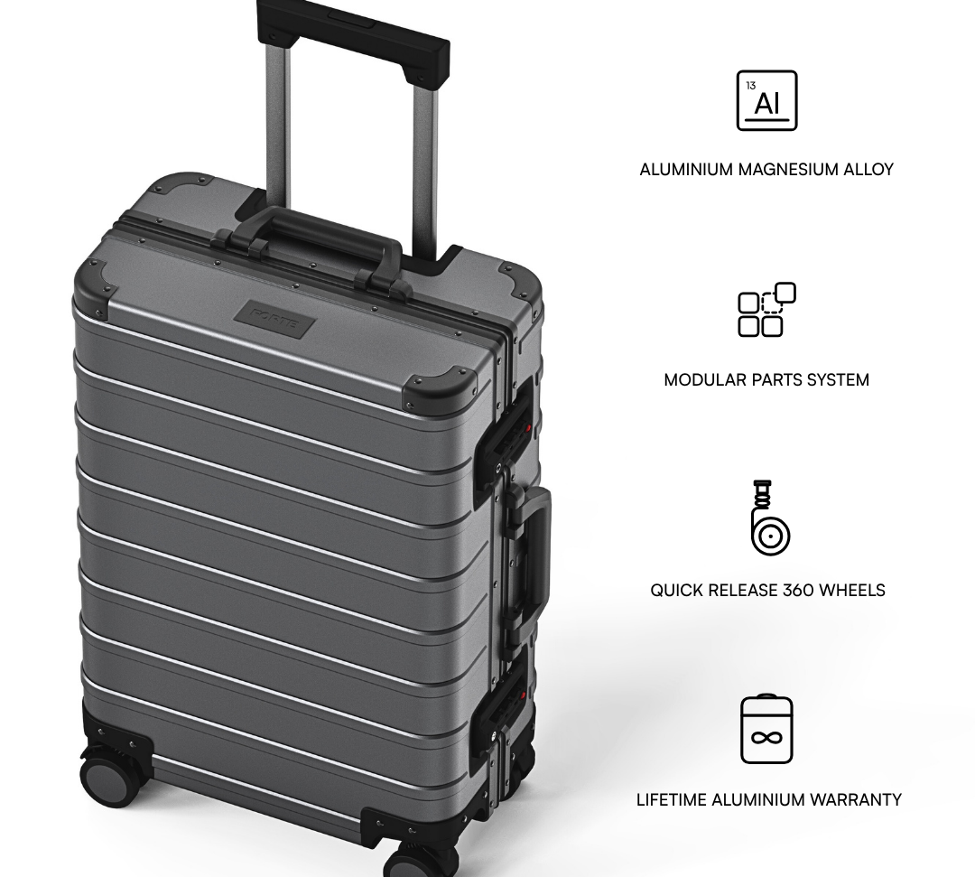 A dark gray hard-shell rolling suitcase shown on a white background with feature callouts and text describing aluminum magnesium alloy construction, modular parts system, quick release 360 wheels, and lifetime aluminum warranty.