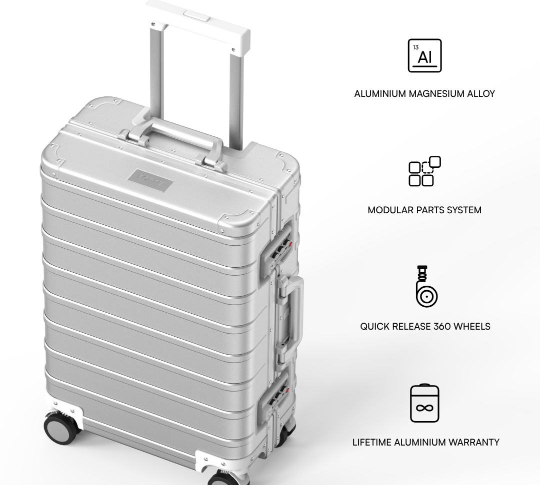 A silver aluminium rolling suitcase with an extended telescopic handle and four spinner wheels, shown on a light gray background with feature callout icons and text describing its materials, modular design, wheels, and warranty.