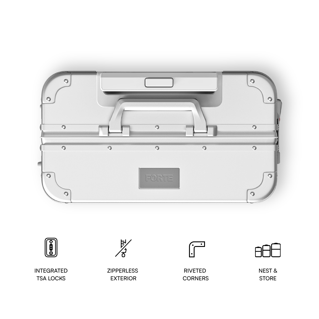 A top-down view of a light gray aluminum hard case with a handle, corner protectors, and a central FORTE logo plate. Below the product are four black line icons and text describing features: integrated TSA locks, zipperless exterior, riveted corners, and nest & store.
